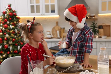 Photo of Cute little children making dough for Christmas cookies in kitchen