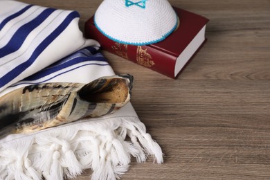 Photo of Tallit, shofar, Torah and kippah on wooden table. Rosh Hashanah holiday symbols