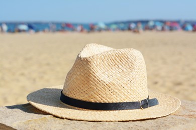 Photo of Stylish straw hat on stone surface near sea