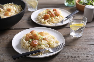 Photo of Delicious scallop pasta with onion served on wooden table, closeup