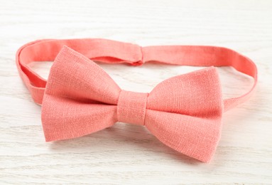 Photo of Stylish pink bow tie on white wooden background, closeup