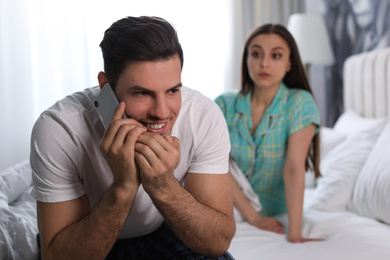 Distrustful young woman eavesdropping on boyfriend at home. Jealousy in relationship
