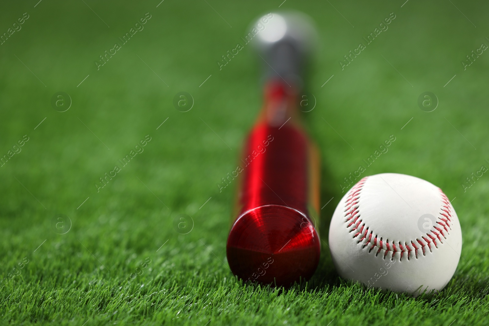 Photo of Baseball bat and ball on green grass, closeup. Space for text