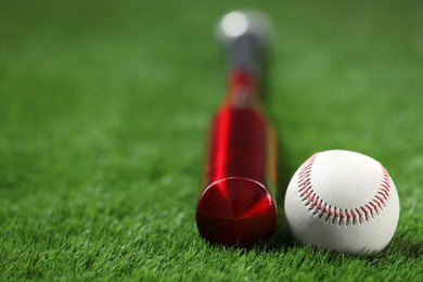 Baseball bat and ball on green grass, closeup. Space for text