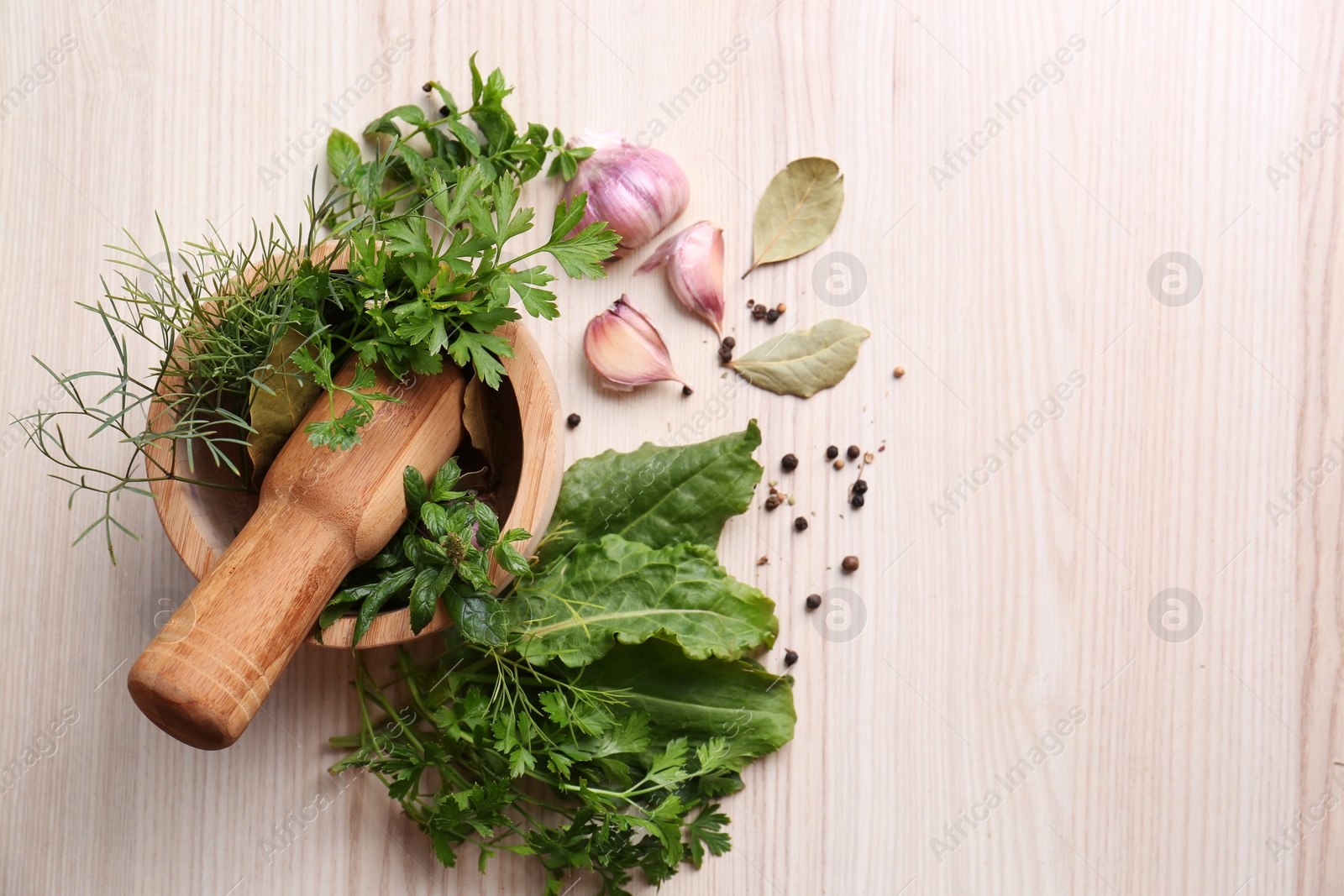 Photo of Mortar with pestle and different ingredients on wooden table, flat lay. Space for text