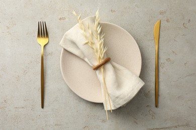 Stylish setting with cutlery, napkin, dry branch and plate on light table, top view