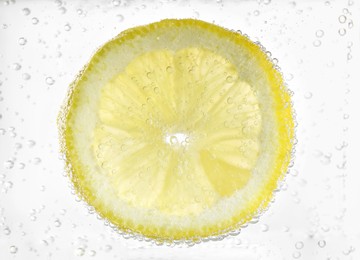 Photo of Juicy lemon slice in soda water, closeup