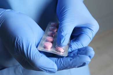 Photo of Doctor taking pill out from blister pack on grey background, closeup