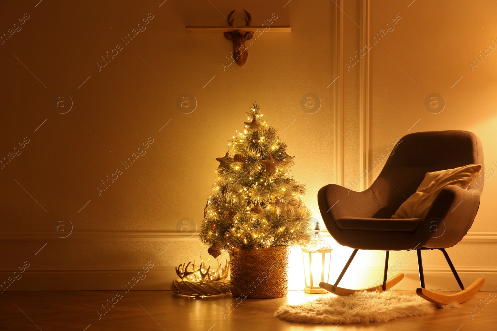 Photo of Beautiful Christmas tree, lantern and rocking chair near wall in room. Space for text