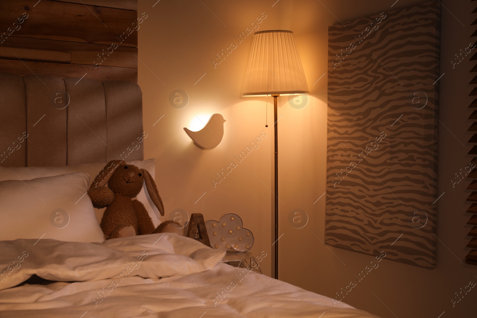 Photo of Glowing lamps near bed in child's room at night