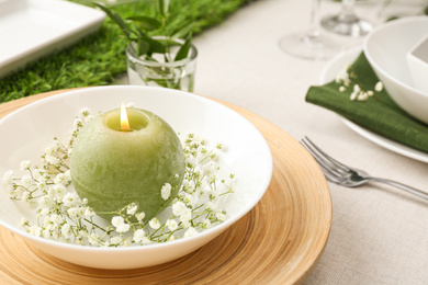 Photo of White plate with candle and flowers, closeup. Festive setting