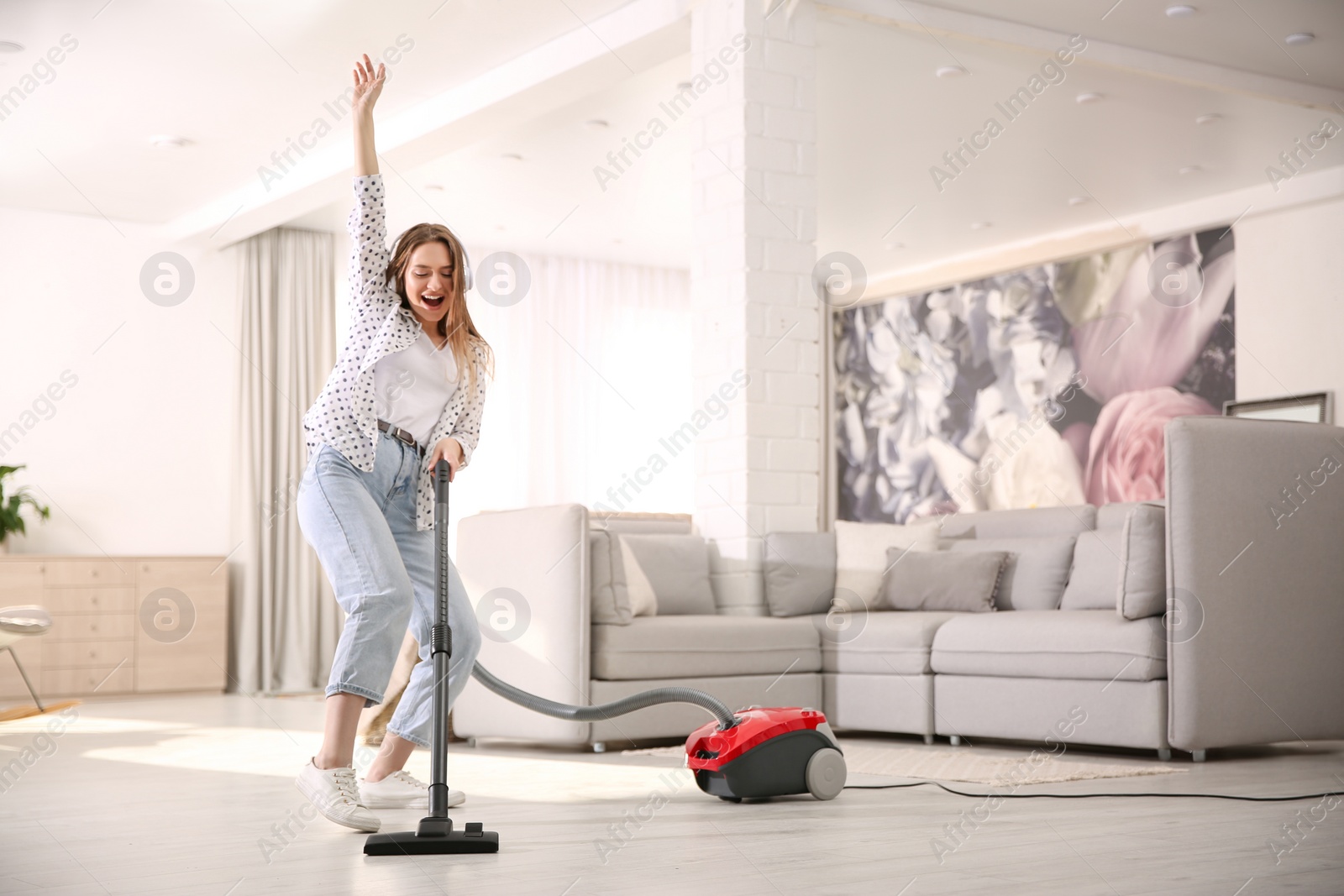 Photo of Young woman having fun while vacuuming at home