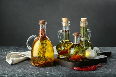 Photo of Cooking oil with different spices and herbs in jugs on light grey table