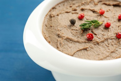 Photo of Tasty liver pate with pepper and herb in bowl on blue table, closeup