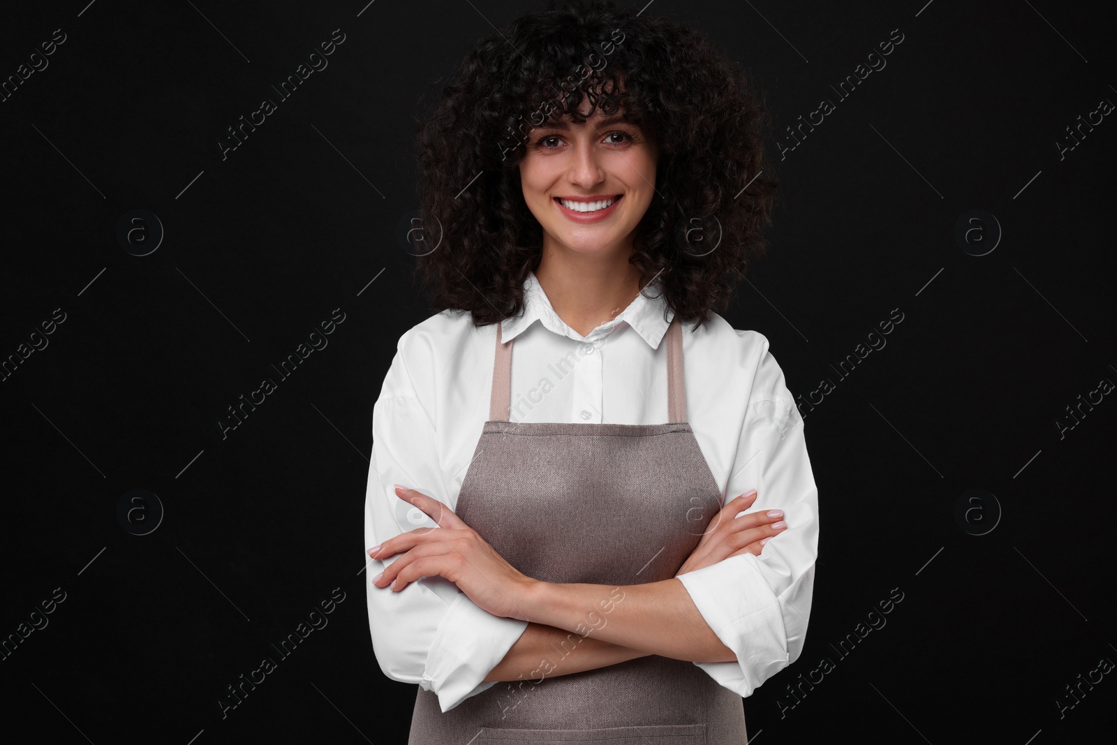 Photo of Happy woman wearing kitchen apron on black background. Mockup for design