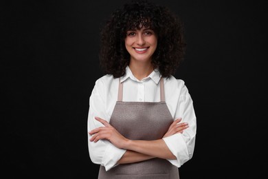 Happy woman wearing kitchen apron on black background. Mockup for design