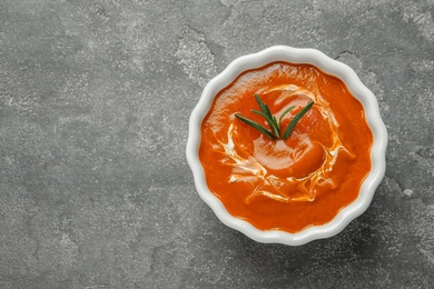 Bowl with fresh homemade tomato soup and space for text on grey background, top view