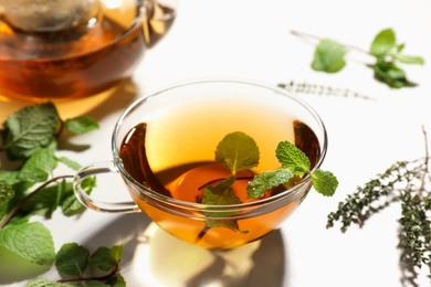 Photo of Aromatic herbal tea with mint and thyme on white table, closeup