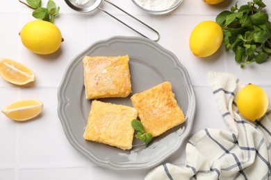 Tasty lemon bars and mint on white tiled table, flat lay