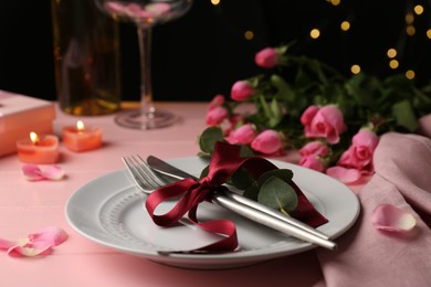 Photo of Place setting with roses and candles on pink wooden table, closeup. Romantic dinner