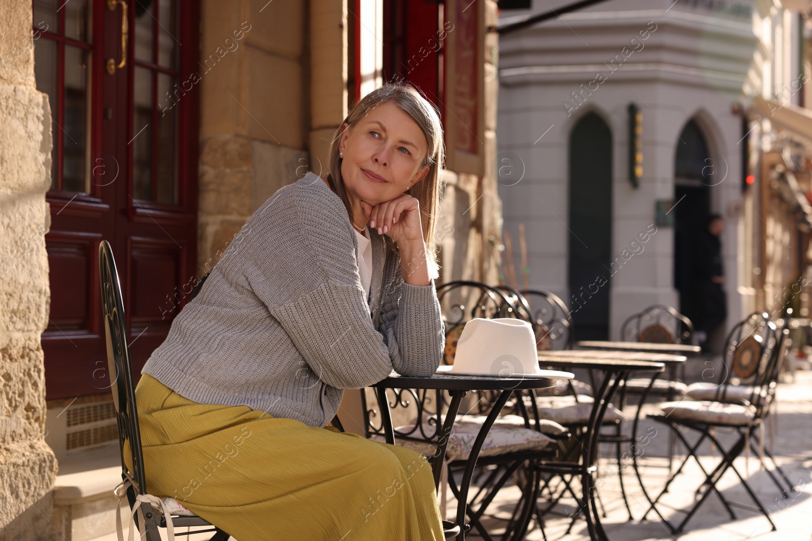 Photo of Beautiful senior woman sitting in outdoor cafe, space for text