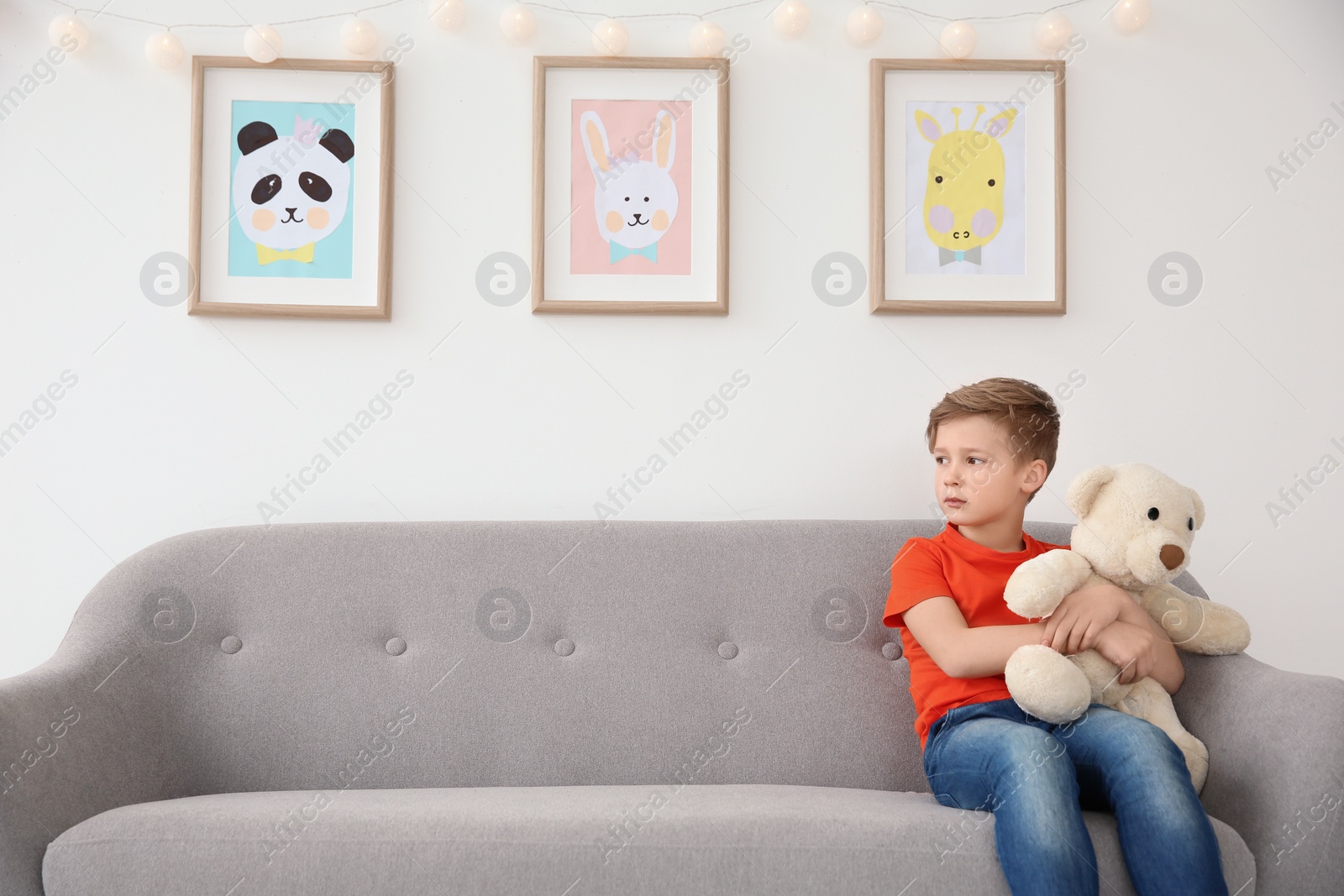 Photo of Little autistic boy sitting on sofa with toy at home