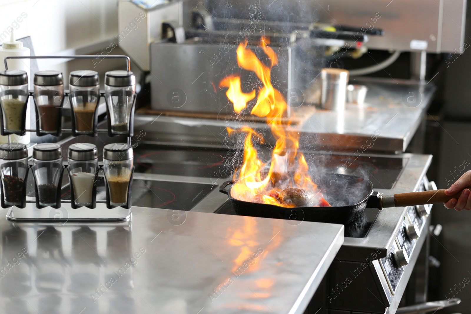 Photo of Cooking meat with burning flame in restaurant kitchen
