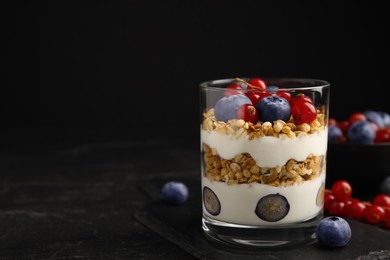 Photo of Delicious yogurt parfait with fresh berries on black table, space for text