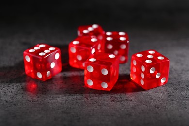 Many red game dices on grey textured table, closeup