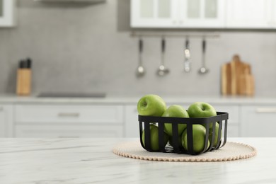 Fresh green apples on white table in kitchen, space for text