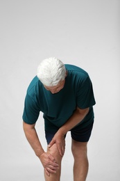 Photo of Senior man having knee problems on grey background