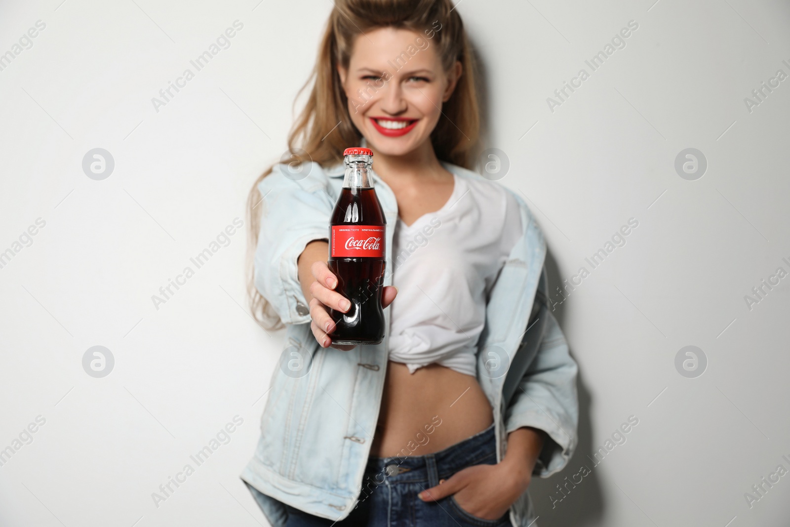 Photo of MYKOLAIV, UKRAINE - NOVEMBER 28, 2018: Young woman with bottle of Coca-Cola on white background