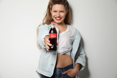 Photo of MYKOLAIV, UKRAINE - NOVEMBER 28, 2018: Young woman with bottle of Coca-Cola on white background