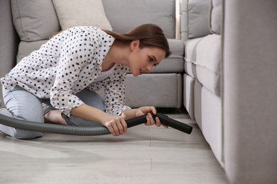 Young woman using vacuum cleaner at home