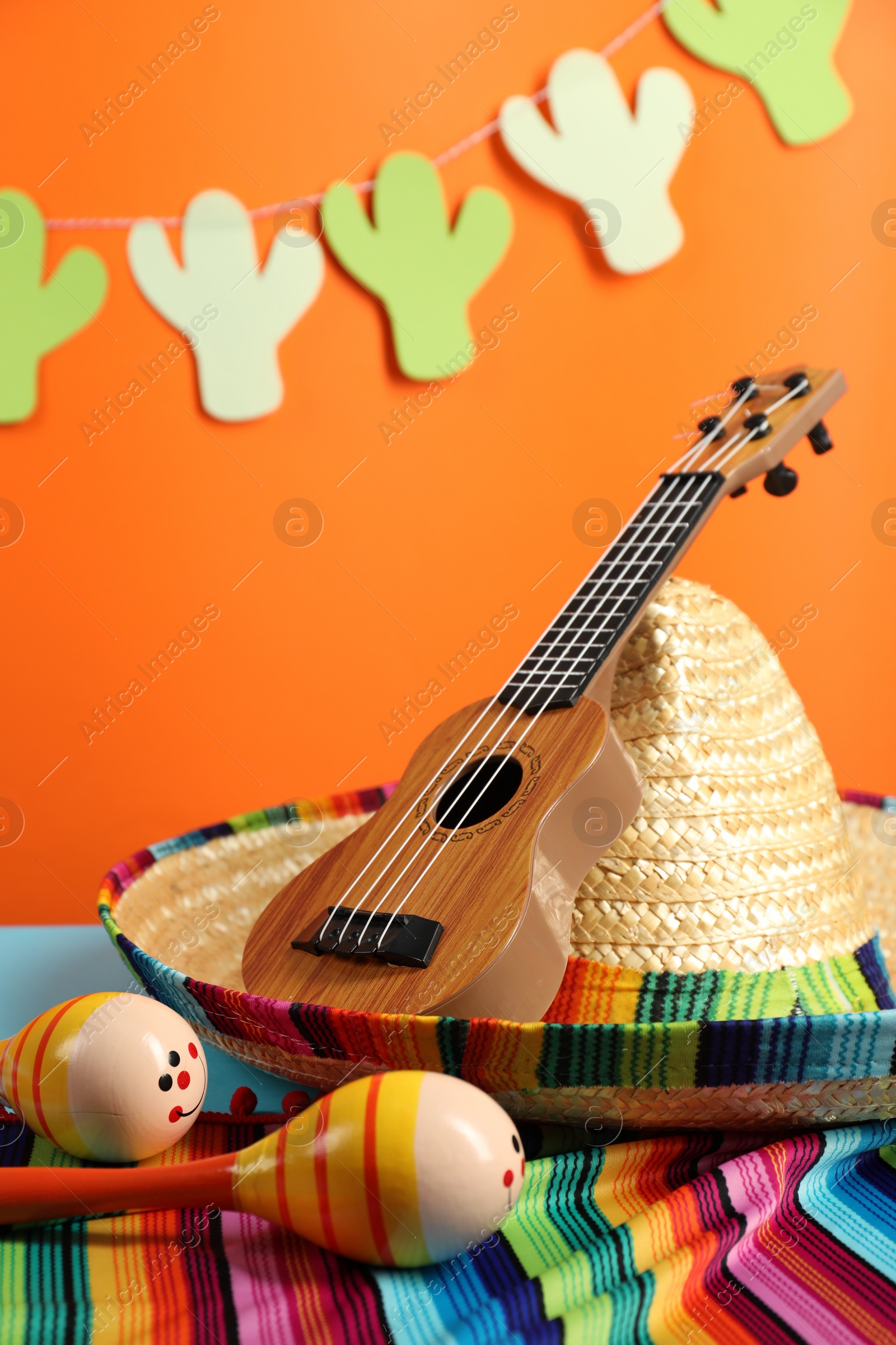 Photo of Mexican sombrero hat, maracas and ukulele on table, closeup