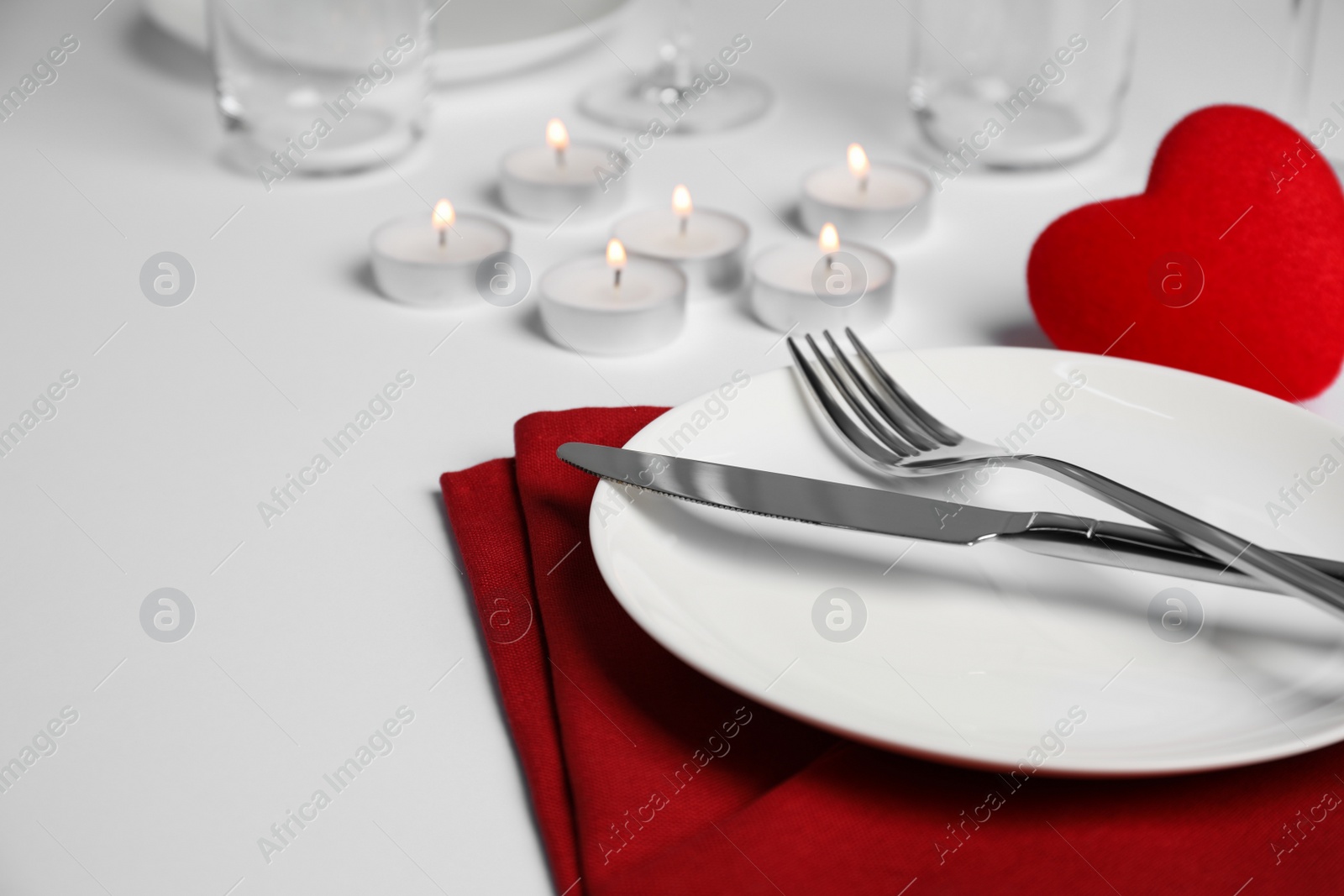 Photo of Beautiful table setting with burning candles on white table, closeup. Romantic dinner. Space for text