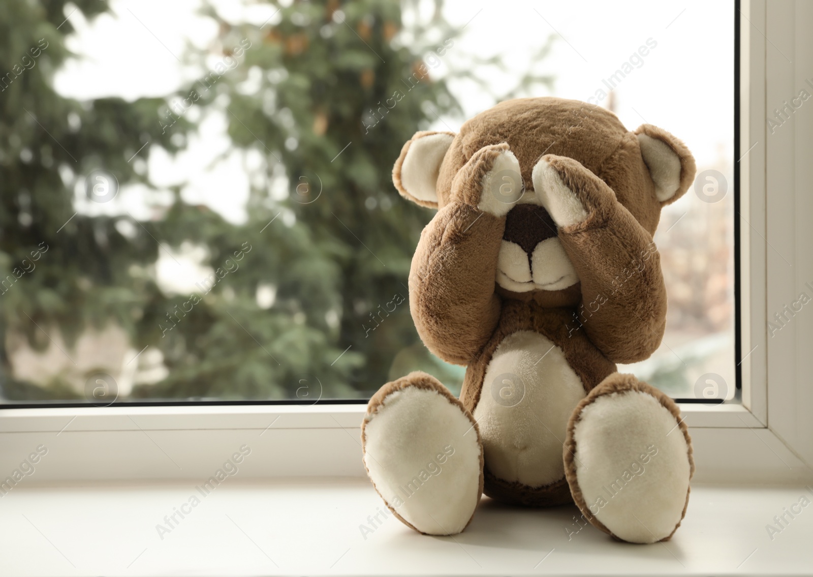 Photo of Cute lonely teddy bear on windowsill indoors. Space for text
