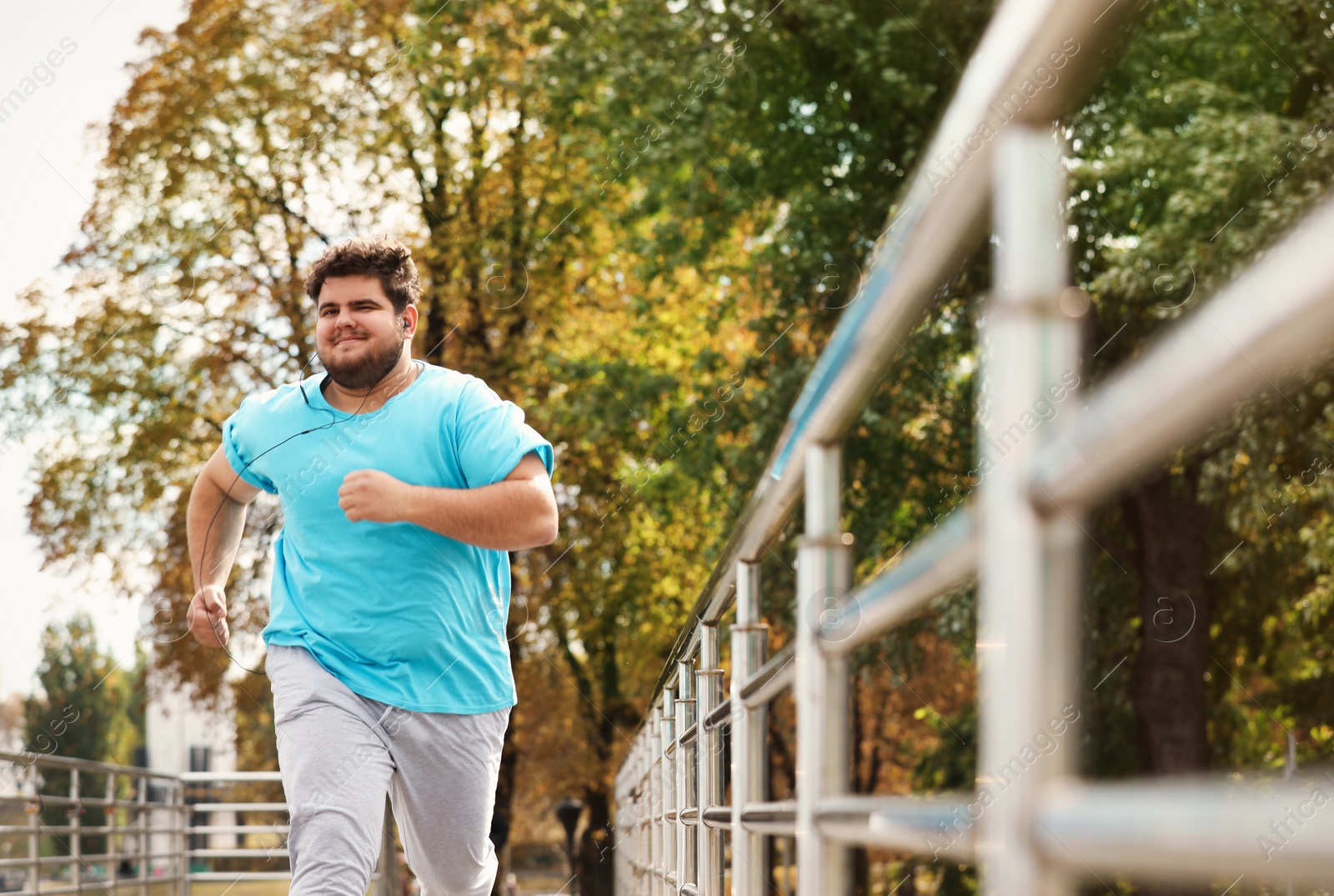 Photo of Young overweight man running outdoors. Fitness lifestyle