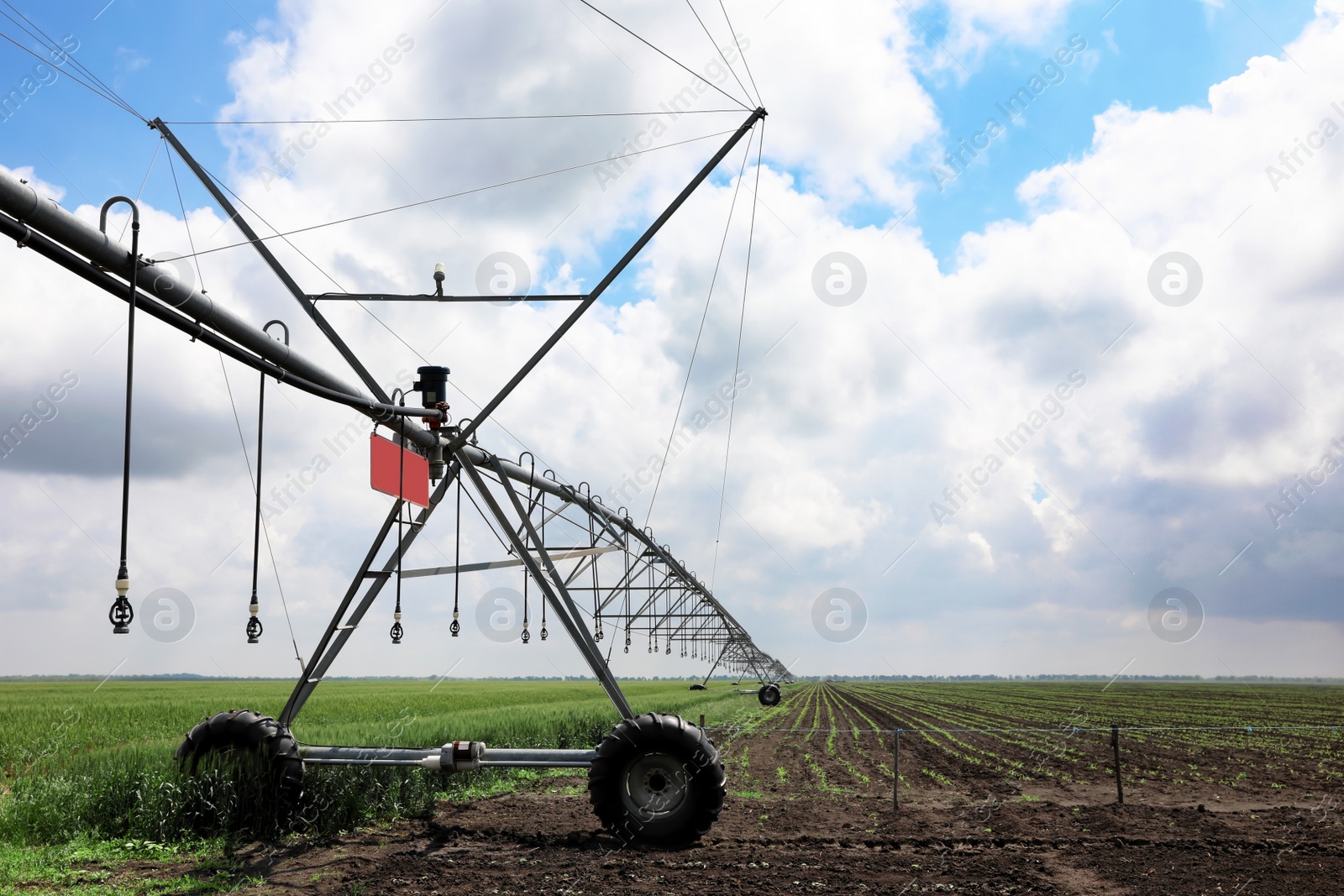 Photo of Modern irrigation system in field under cloudy sky. Agricultural equipment