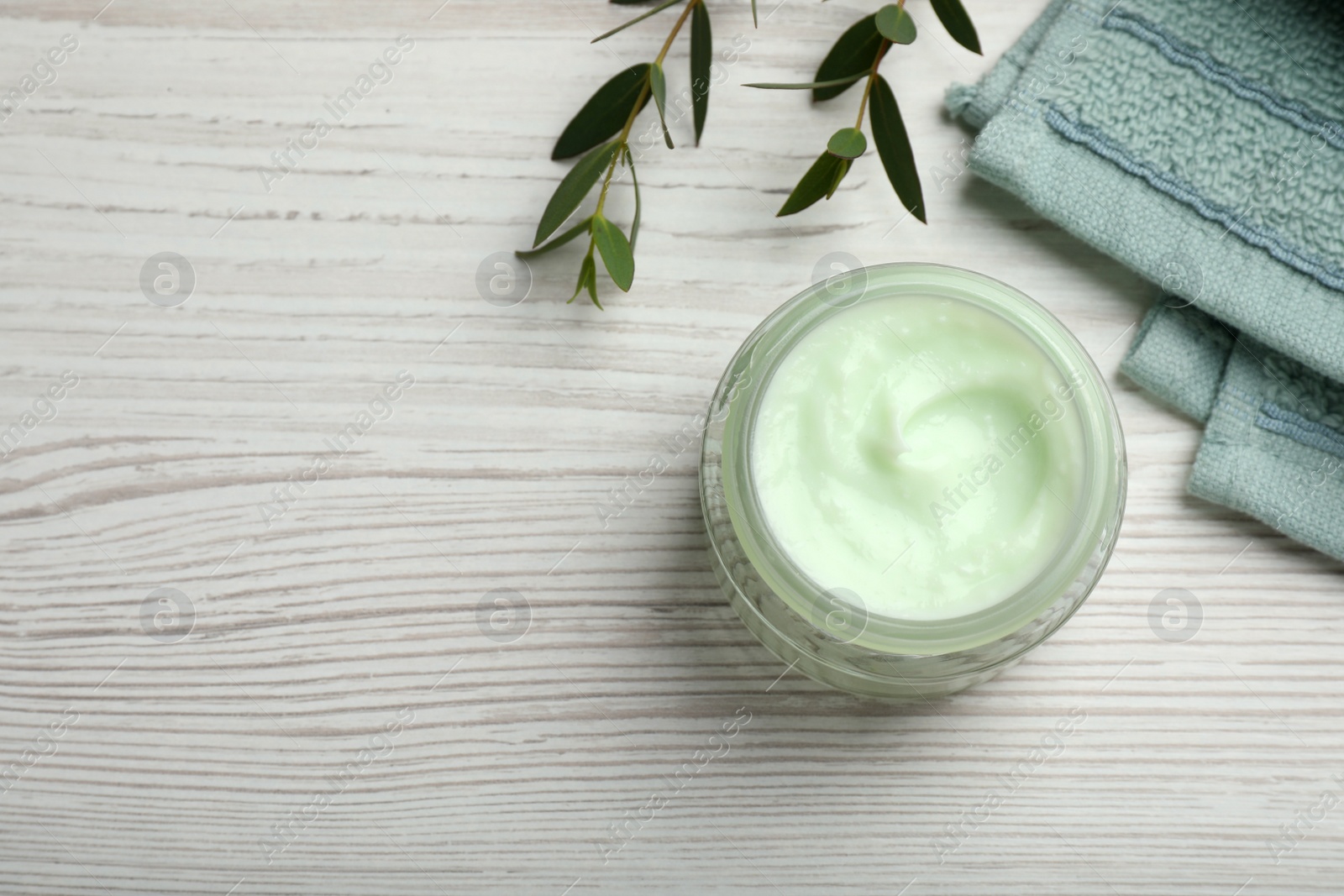 Photo of Jar of organic cream, towel and eucalyptus on white wooden table, flat lay. Space for text