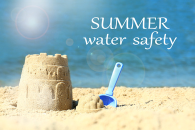 Image of Summer water safety. Beautiful view of beach with sand figure and shovel near sea
