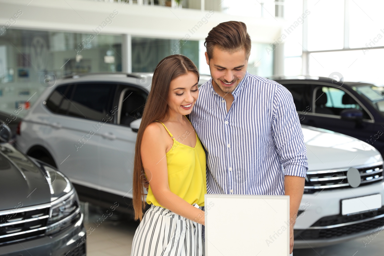 Photo of Young couple choosing new car in salon