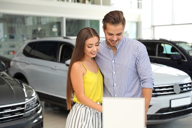 Young couple choosing new car in salon