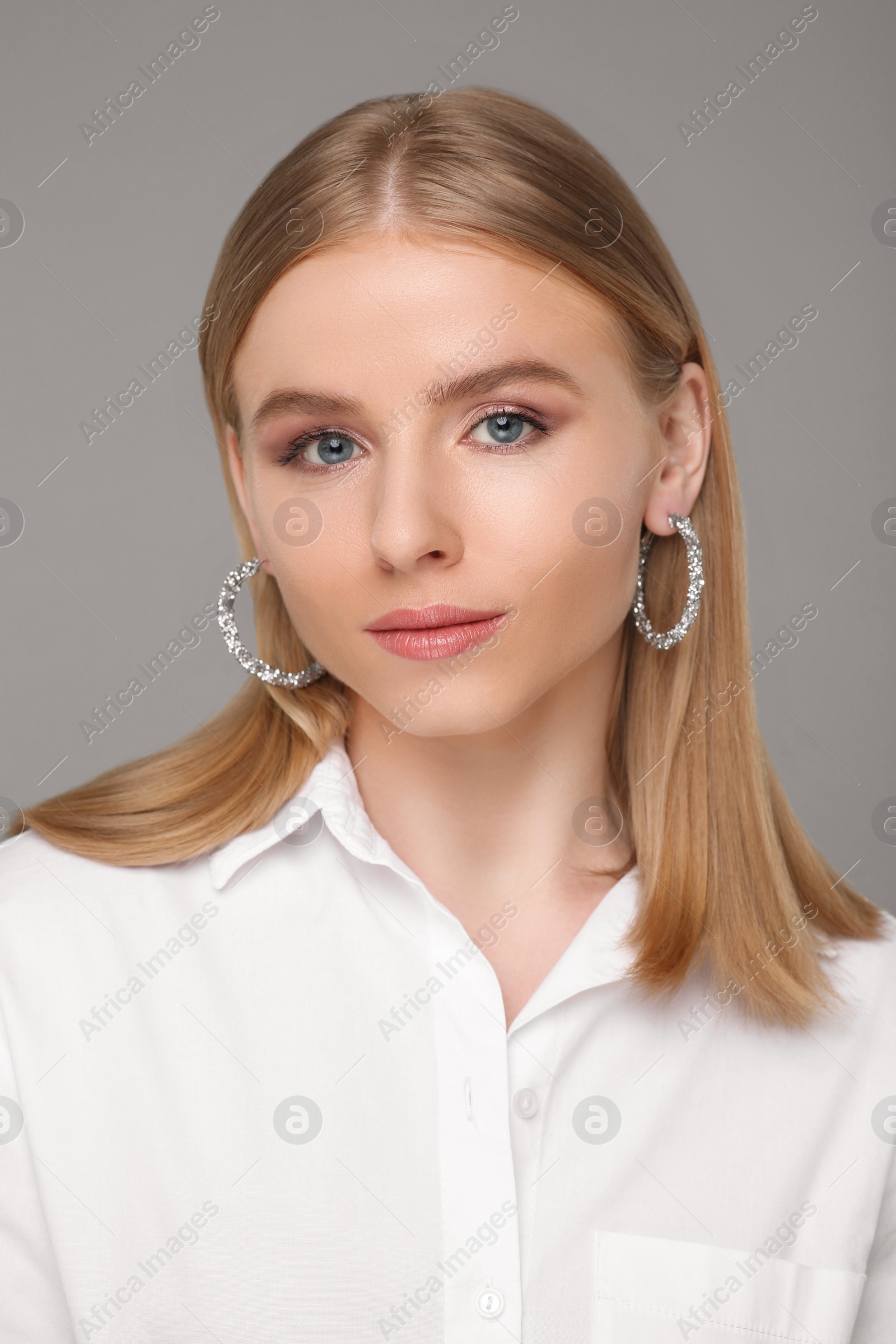 Photo of Beautiful young woman with elegant earrings on gray background