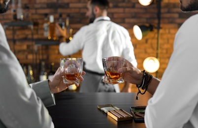 Photo of Friends drinking whiskey together in bar, closeup
