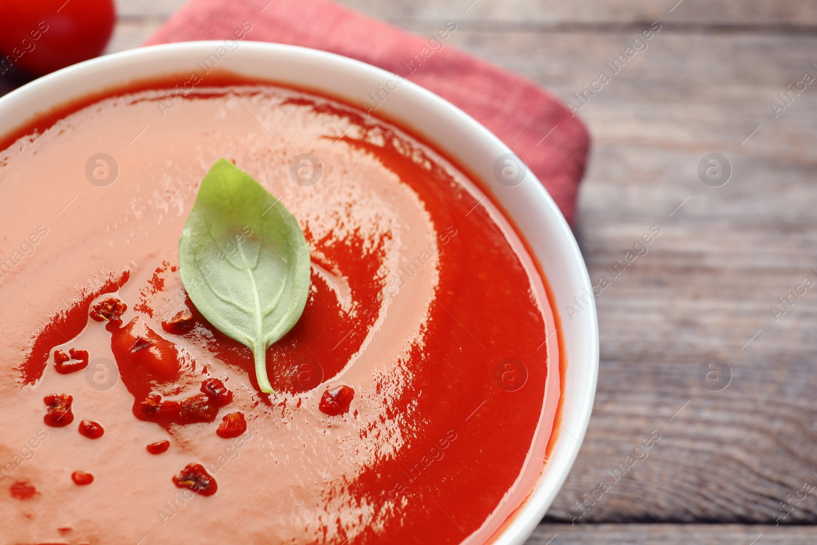 Photo of Bowl with fresh homemade tomato soup on table, closeup