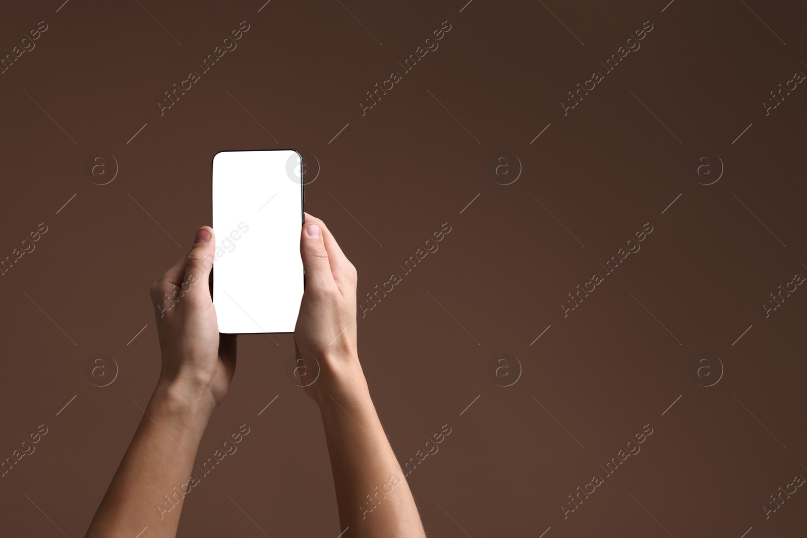 Photo of Man holding smartphone with blank screen on brown background, closeup. Mockup for design