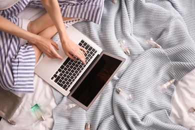 Female blogger with laptop on bed, top view