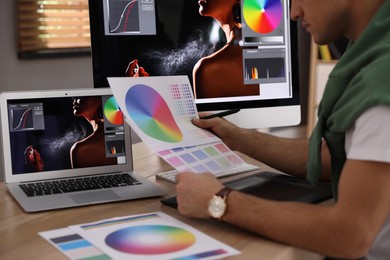 Photo of Professional retoucher with color palettes at workplace indoors, closeup