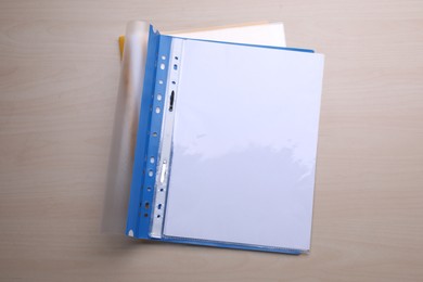 File folder with punched pockets and paper sheets on wooden table, top view